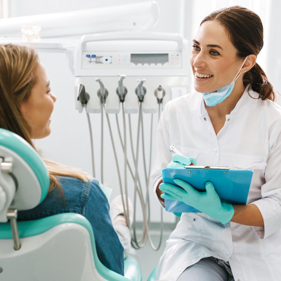 A young woman discussing her treatment with her dentist