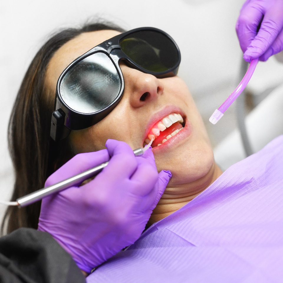 A dentist using a diode laser to treat a woman’s gum disease