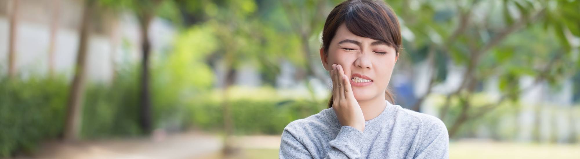 Woman in need of emergency dentistry holding cheek in pain