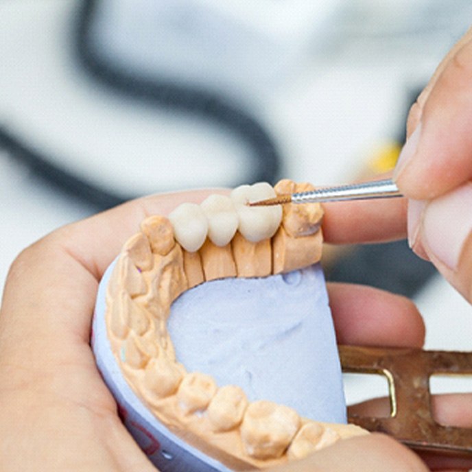 wA dental technician working on a dental bridge