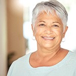 Senior woman in light blue shirt at home smiling