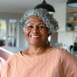 Senior woman in pink shirt smiling at home