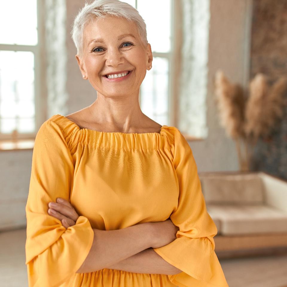 Senior woman with yellow shirt at home smiling