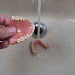 Hand holding denture above sink