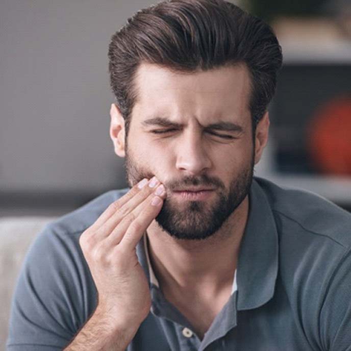 Pained man who needs to visit his St. John’s emergency dentist 