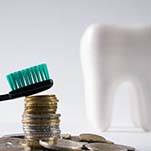 Toothbrush sitting on top of coins near model tooth