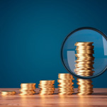 Magnifying glass inspecting a stack of increasingly taller coins