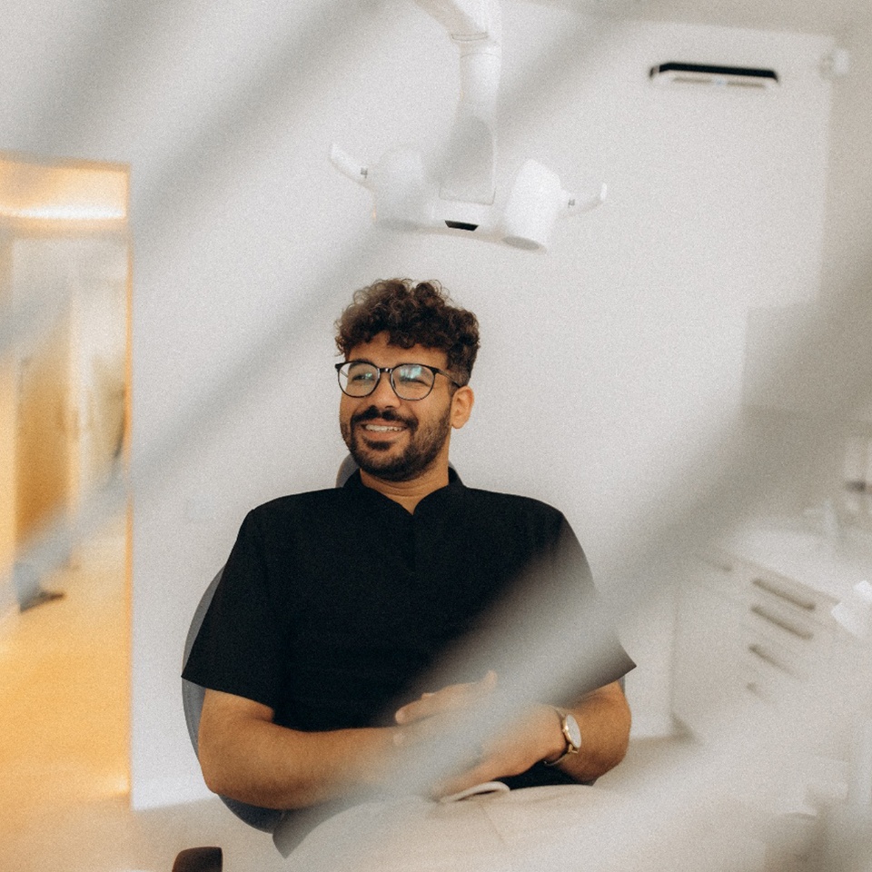 Patient with black glasses smiling in treatment chair