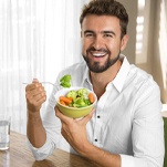 man eating healthy foods as a health benefit of dental implants in St Johns