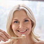 An older woman brushing her teeth