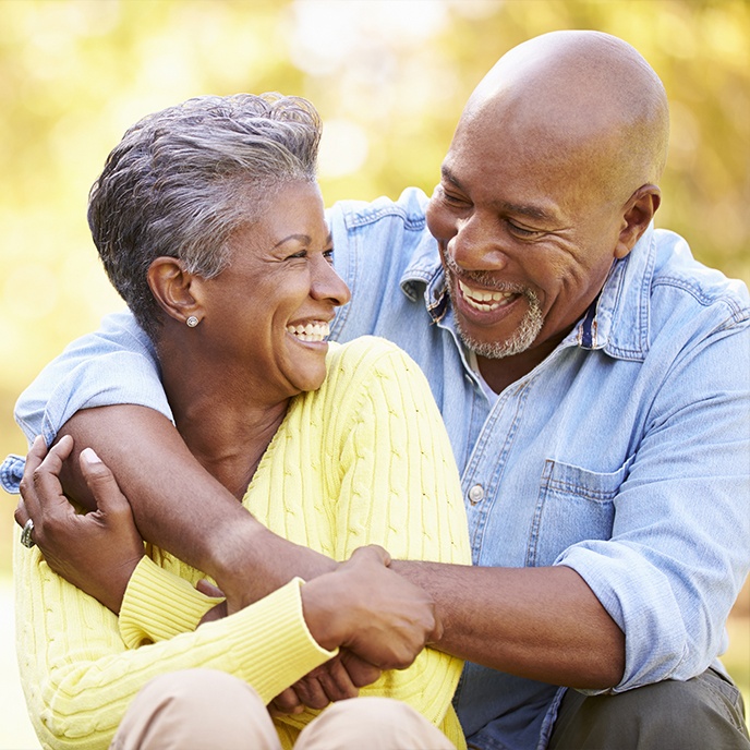 Man and woman smiling after dental implant tooth replacement