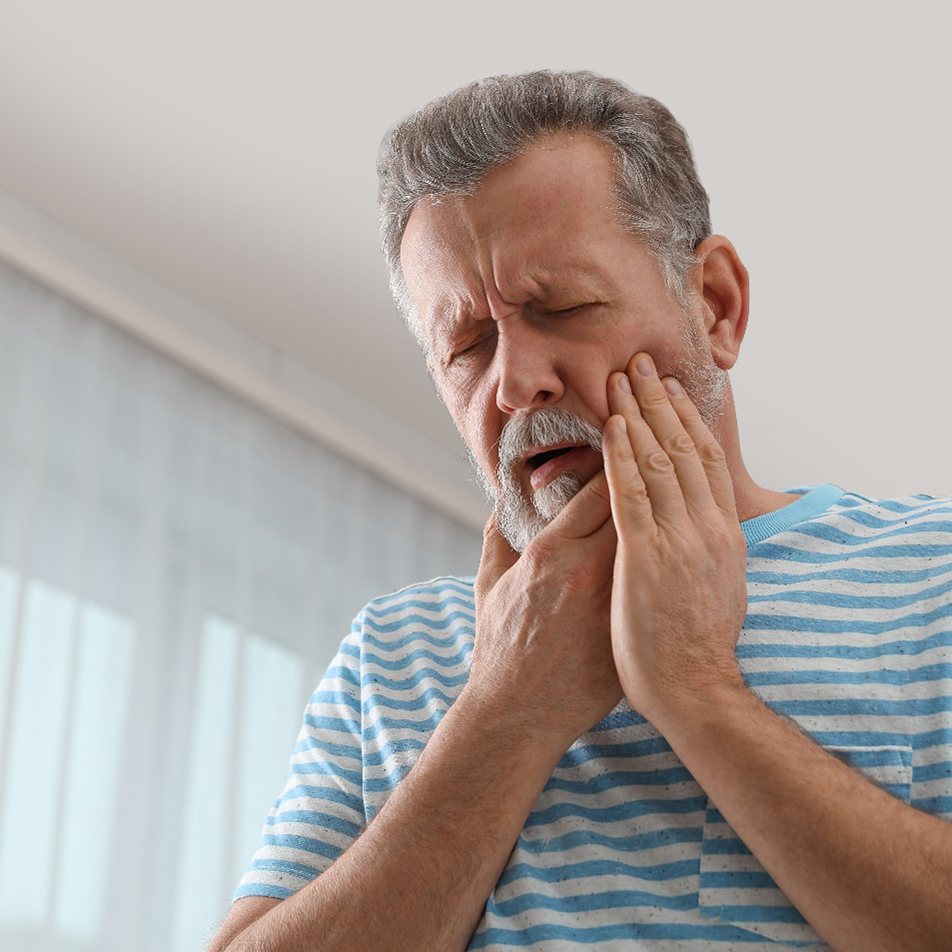 Man in striped shirt rubbing jaw in pain