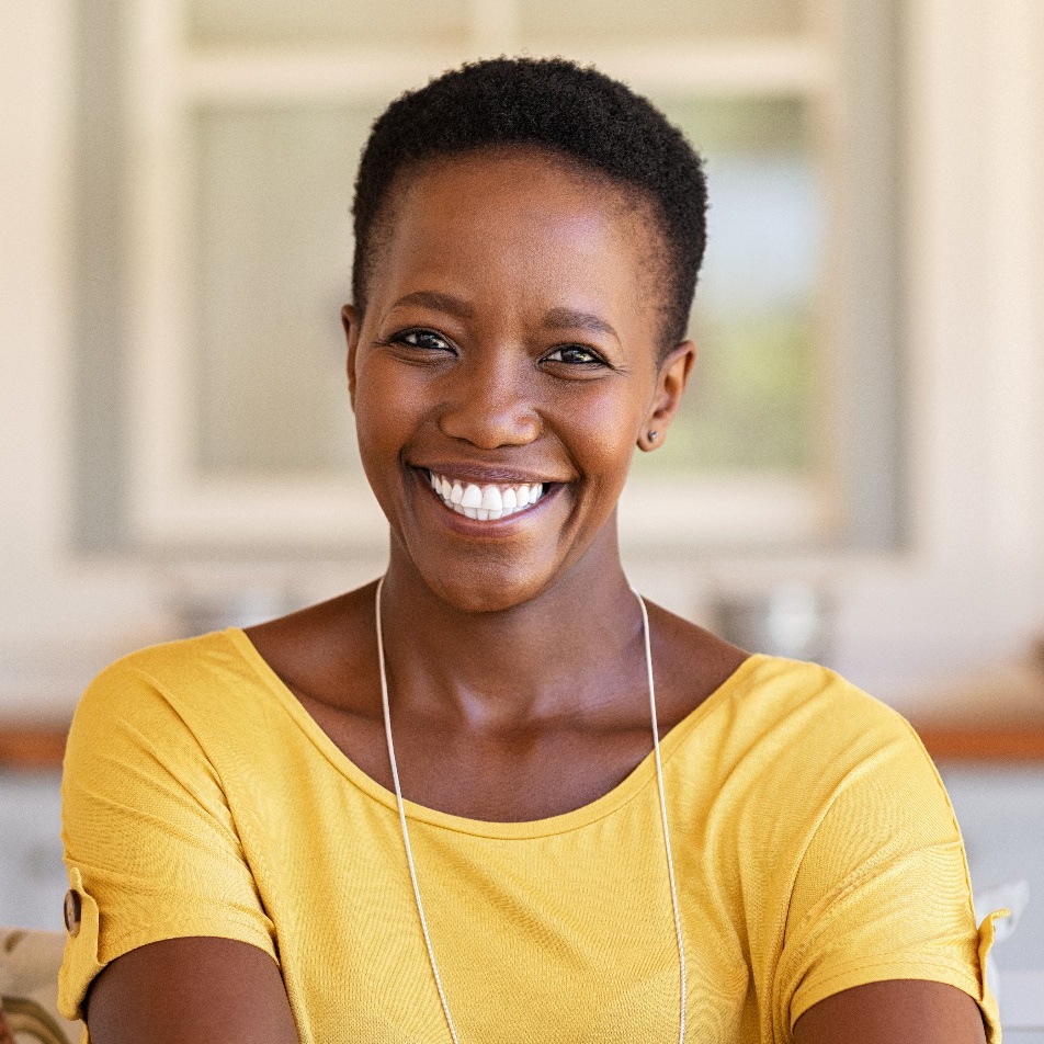 Woman with yellow shirt sitting at home smiling