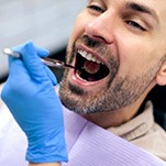 A hygienist checking a man’s mouth for oral cancer
