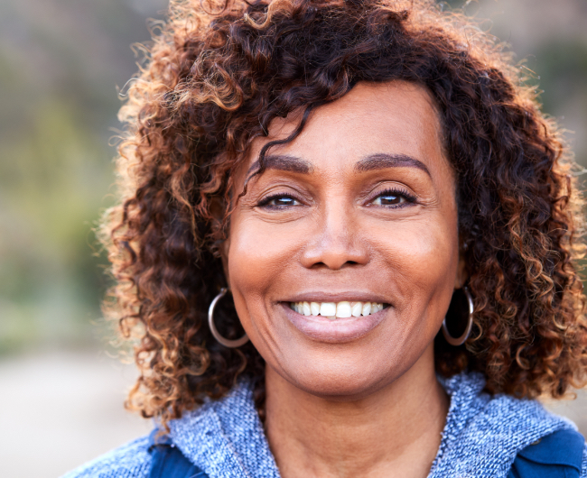 Woman with flawless smile after replacing missing teeth