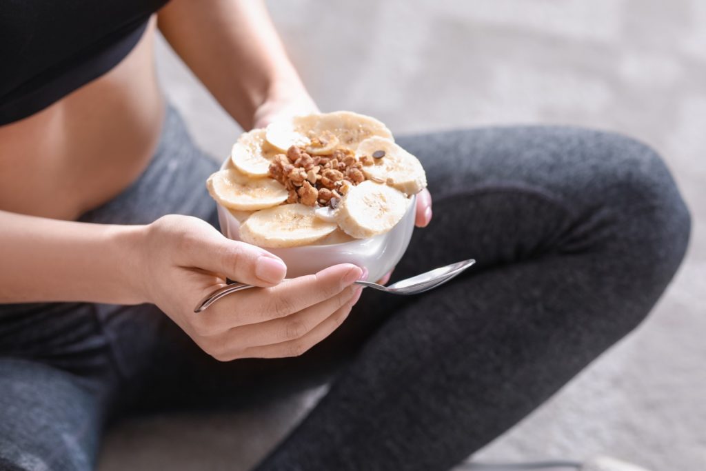 Closeup of woman eating yogurt with bananas on top