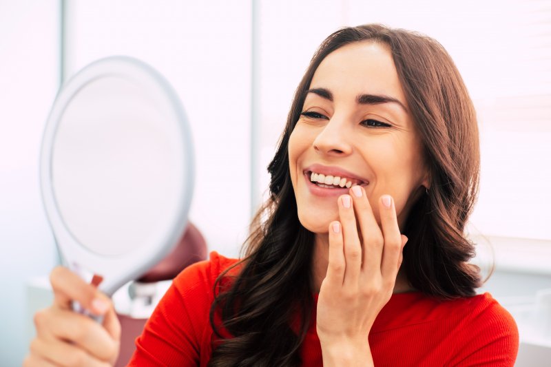 A woman looking at her new dental implants in a mirror