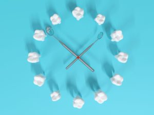 Fake teeth and dental mirrors arranged like a clock on a blue background